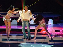 Young man singing, with two young women removing his shirt