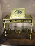 Louis XVI style writing table of Marie-Antoinette; by Adam Weisweiler; 1784; oak, ebony and sycamore veneer, Japanese lacquer, steel, bronze gilt; 73.7 x 81. 2 cm; Louvre[63]