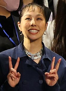 Portrait of Ai wearing a navy blue outfit while posing a V sign formed with both of her hands