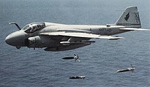 An A-6E Intruder of Attack Squadron 85 dropping bombs while flying over a large body of water in 1992