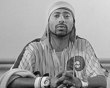 Photo of a man with a short goatee and mustache wearing a durag