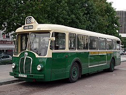 Photo de trois-quart avant d'un autobus au couleur de la RATP en stationnement le long d'un trottoir.