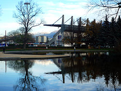 Un plan d'eau au premier plan devant une tribune de stade et des arbres