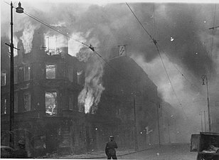 NARA copy #27, IPN copy #23 Destruction of a housing block Zamenhofa Street looking North, with burning Zamenhofa 25 / Wołyńska 2 on the left.
