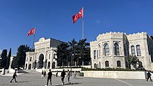 A triumphal arch adjacent to a Turkish flag and in front of an open plaza
