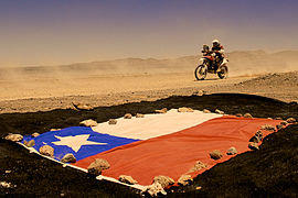Calama. Le motocycliste français Mathieu Serradori passe devant un drapeau du Chili.