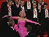 A lady in pink dress surrounded by gentlemen