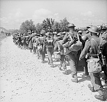 A column of British troops march down a road