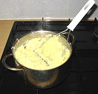 A potato masher in use