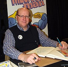 Simpson seated at a table smiling