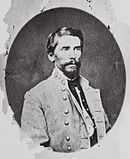 Black and white photo shows a dark-haired, bearded man wearing a gray uniform with three stars on the collar.