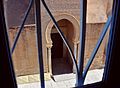 Vue du porche de Bab al-Ma depuis une fenêtre grillagée. Il est ouvert par un arc outrepassé brisé.