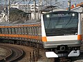 中央線快速電車のステンレス製E233系。ラインカラーのオレンジバーミリオンが帯の色として現れている。