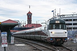 A passenger train with white, dark brown, and dark green stripes.