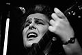 Photo en noir et blanc d'une femme qui chante en s'accompagnant à la guitare.