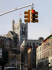 Photo couleurs de la tour et des bâtiments d'une université à New York, avec en premier plan des feux rouges.