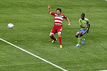 Zakuani vies against a Dallas player for the ball