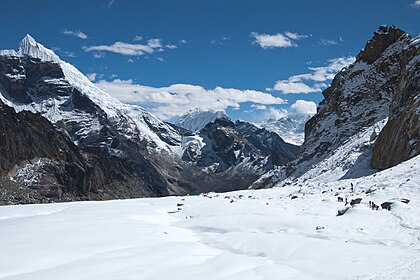 Vista para o leste de Cho La (5 400 m de altitude), um passo de montanha ao sul da cordilheira do Himalaia, na zona do Everest, no Nepal: campo glacial coberto de neve, penhascos negros expondo camadas geológicas e um pequeno lago glacial no vale à frente. (definição 4 028 × 2 687)