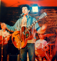 Photograph of a man playing a guitar onstage