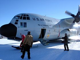 L'équipage de fret du pôle Sud décharge les passagers d'un LC-130. au sol.