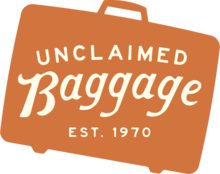 A silhouette of a suitcase with the text "Unclaimed Baggage, Est. 1970"