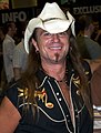 A man with a cowboy hat, long hair, and a coat