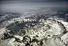 Aerial view of large, snowy crater, surrounded by mountains