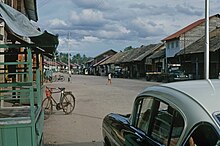 A view down a street with a couple of cars and pedestrians