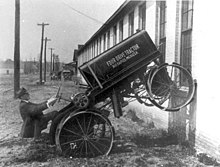 Un tracteur en équilibre les roues avant sur un mur.