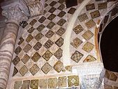 Photographie des carreaux de céramique lustrée, monochromes et polychromes, qui ornent le mihrab et son mur. Leurs décors variés comportent divers ornements géométriques, floraux et végétaux.