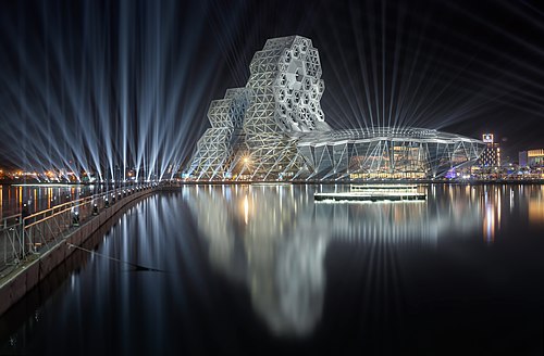 Exterior of the Kaohsiung Music Center illuminated at night and reflected in water