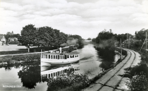 S/S Karö stävar fram längs Ronnebyån på väg ut mot havet. Till höger i bild syns Mellersta Blekinge järnvägs spår till Ronneby hamn. Fotografi ur Sjöhistoriska museets samlingar.