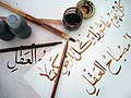 The instruments and work of a student calligrapher. The phrase written on the top of the paper shows the Shiite saying "Every day is Ashura and every land is Karbala."