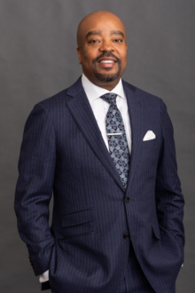 Dr. Michael A. Lindsey stands in a pinstripe suit with his hands in his pockets.