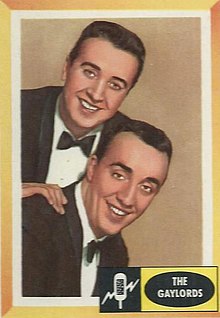 Two men in suits and bowties smile and pose, with Ronnie Gaylord leaning above Burt Holiday. There is a small yellow box in the bottom corner identifying them as The Gaylords.