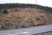 Three eras of deposition and two discordances are visible in this highway cut in the Netherlands. Note the color and slight angular change between the lower red bed layering and the middle strata. The upper strata are tilted yet again relative to the bottom layerings well demonstrating the cycles this land formation went through as part of the sea floor.