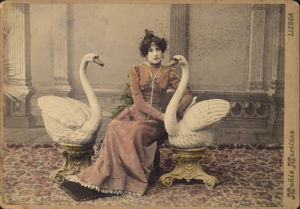 Cláudia de Campos poses for a portrait with two swan sculptures