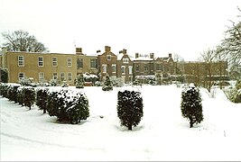 Photo d'un long bâtiment au milieu d'un parc sous la neige