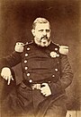 Photo en noir et blanc d'un homme âgé portant une barbe et assit sur une chaise avec un uniforme à épaulettes de général.