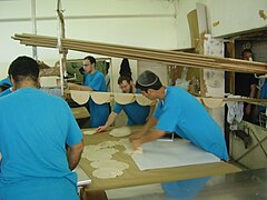 Rolling the matzahs and placing them on a stick that enters the oven in the bakery in Kfar Chabad