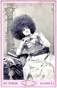 Photographie promotionnelle d'une charmeuse de serpents aux cheveux crépus.