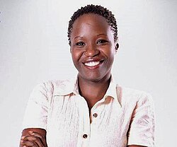 Akite Agnes wearing an off-white, short-sleeved top, grinning at camera