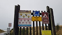 Sign board at beach entrance with warning about speed limit, drift wood, waves, etc.