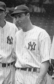 Medium-wide shot of baseball player Joe DiMaggio, wearing a "NY" hat and shirt.