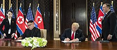 Donald Trump and Kim Jong-un seated at a table