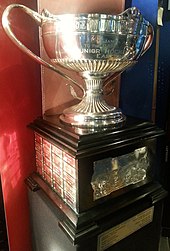 Trophy with a large ornate silver bowl mounted on a square wooden base on display at the Hockey Hall of Fame