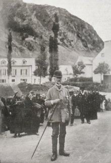 Photographie d'un homme devant un autre groupe de personnes.