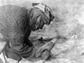 Une femme pied-noir grattant la graisse d'une peau à l'aide d'un os en 1928