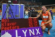 Photo of Femke Bol crouching next to an electronic score board that indicates a time of 49.26 seconds