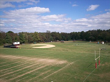 Campus view from the top row of the football stadium looking east. A football practice field is in the foreground, followed by the baseball field, and the softball field